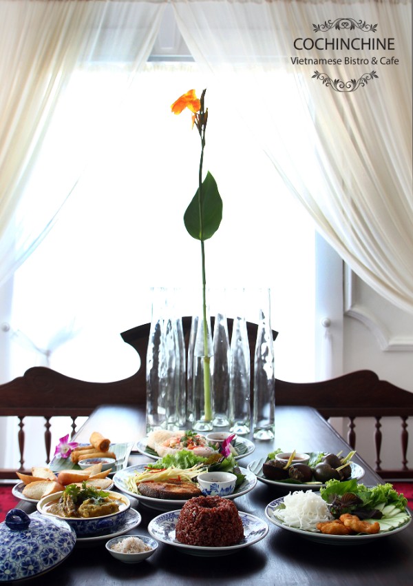 Traditional Vietnamese Meal with brown rice, fried fish, duck spring rolls, lotus salad, curry ...